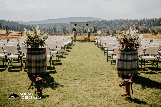 White ceremony chairs and a wooden arbor facing the valley