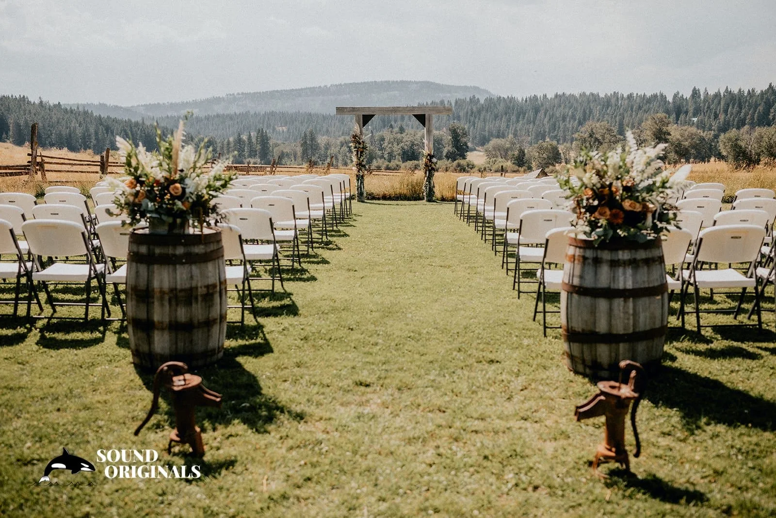 White ceremony chairs and a wooden arbor facing the valley